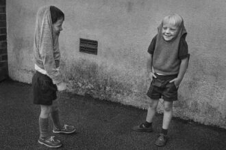 Two boys with their jumpers over their heads, Booker Avenue Primary School, Liverpool (1988)